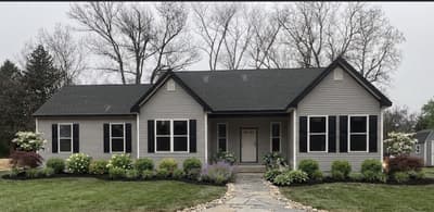 Renovated gray ranch home exterior with black shutters, a stone walkway, and new landscaping by KRidge Construction