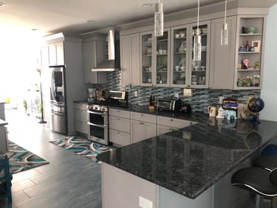 Gray kitchen remodel with glass-front cabinetry and a granite waterfall island