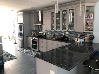Gray kitchen remodel with glass-front cabinetry and a granite waterfall island